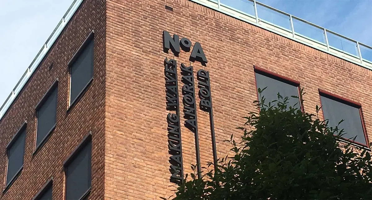 Teglfasade med skilt for NOA og Making Waves